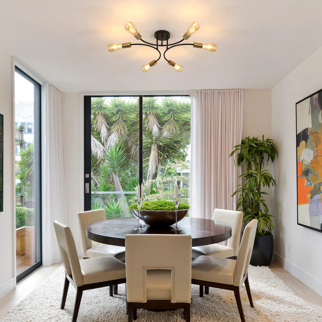 Elegant black and gold chandelier illuminating a modern dining area with a round table and stylish decor.