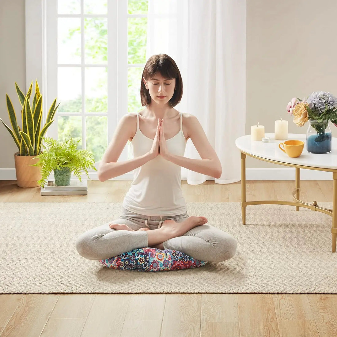 Woman seated in a lotus pose on a boho floor cushion, demonstrating ideal support and padding for yoga or mindfulness practices.
