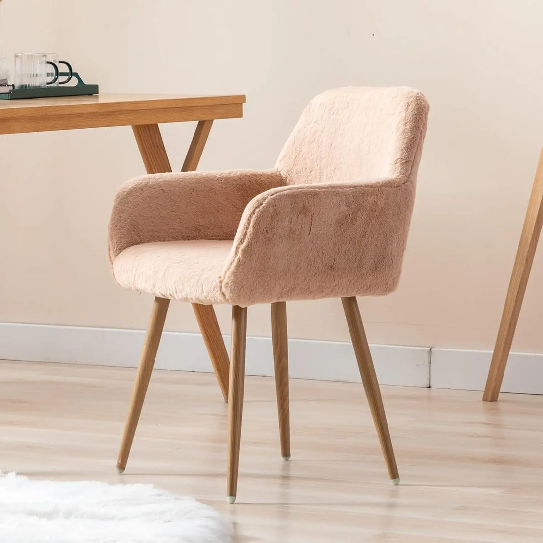 Side profile of a modern camel-colored faux fur chair with comfortable arms and wood legs, perfect for a makeup vanity or desk.

