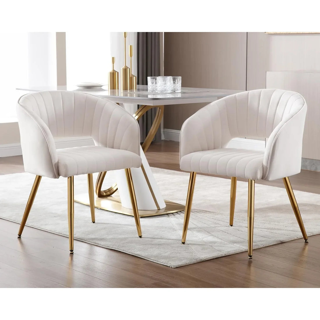 A matching pair of cream velvet upholstered dining chairs with gold metal legs and tufted backs, set around a contemporary dining table.

