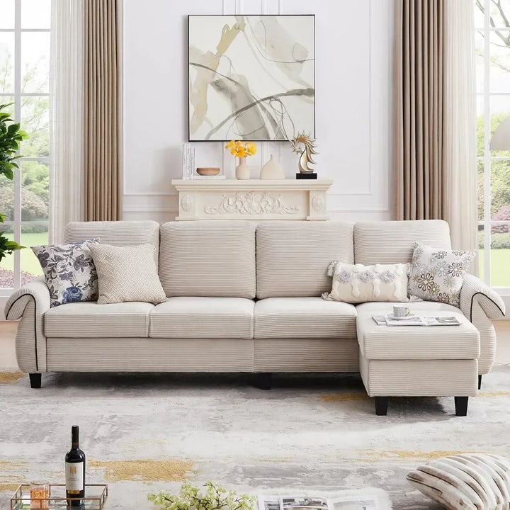 A beige L-shaped sectional sofa with pillows, positioned in a cozy living room with a fireplace and a modern décor.
