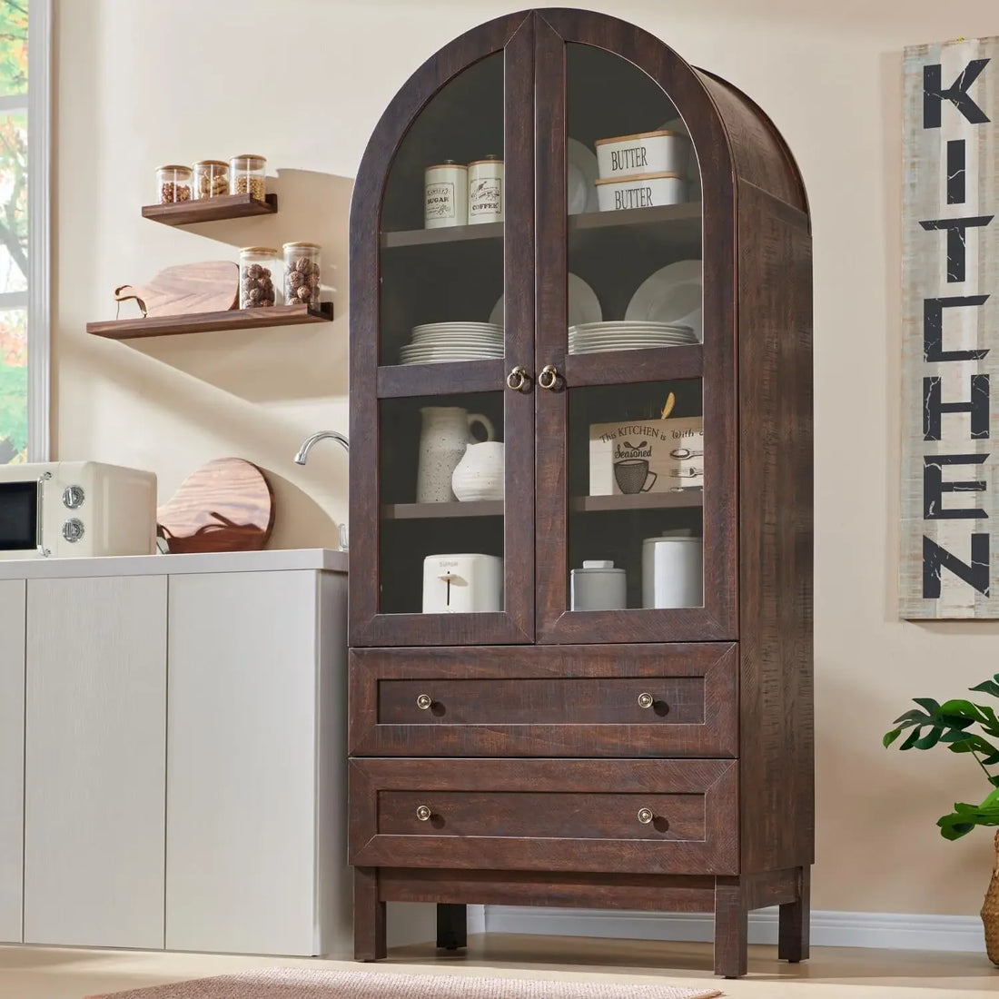 Front view of the 71-inch tall arched kitchen pantry cabinet in a warm brown wood finish with glass doors, adjustable shelves, and two drawers.