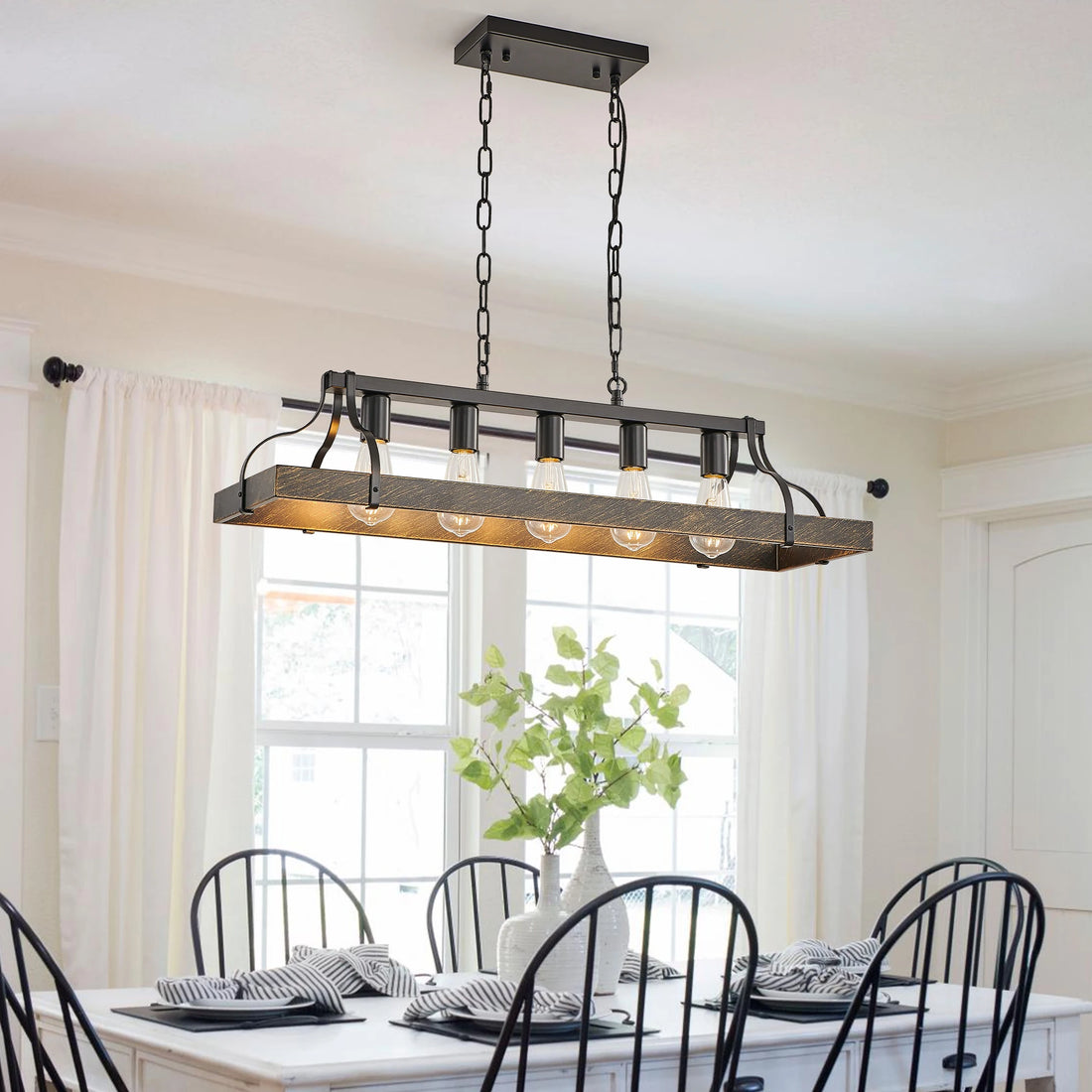 Vintage black and gold chandelier hanging over a dining table with elegant decor.