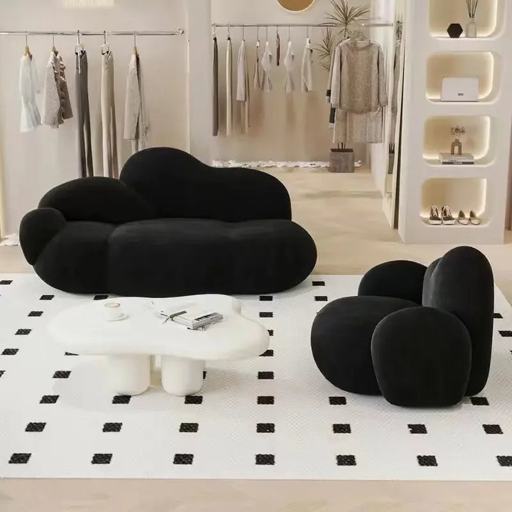 A black Wabi Sabi Nordic cloud sofa and matching armchair displayed in a chic boutique, featuring rounded, pebble-like cushions and a modern minimalist design.

