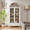 White arched farmhouse cabinet with glass doors and a rustic design for modern kitchen storage.